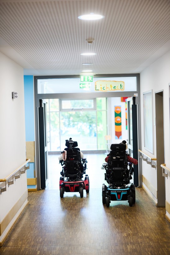 Zwei Kinder mit Elektrorollstühlen