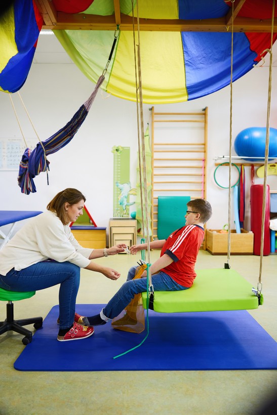Kind auf Therapieschaukel